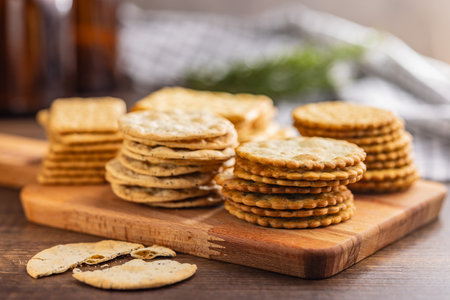 A stack of crackers neatly arranged on a cutting board on a wooden tabletop.