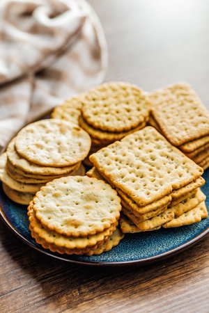 A stack of crackers neatly arranged on a plate on a wooden tabletop.の写真素材
