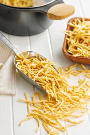 Uncooked spaetzle pasta in scoop on a kitchen table.