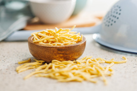 Uncooked spaetzle pasta in a bowl on a kitchen table.