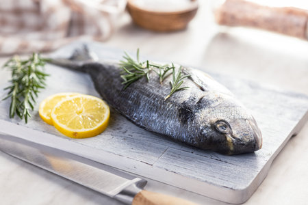 Fresh sea bream fish on a cutting board on a kitchen table.の写真素材
