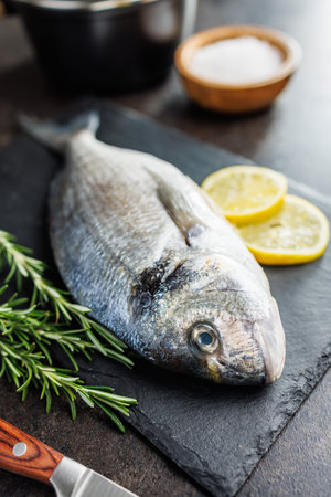 Fresh sea bream fish on a cutting board on a kitchen table.の写真素材