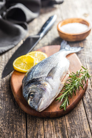 Fresh sea bream fish on a cutting board on a wooden table.の写真素材