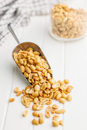 Salted roasted peanuts in a scoop on a kitchen table