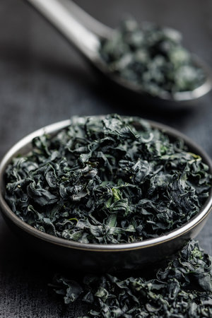 Dried wakame seaweed in a bowl on a black table.の写真素材