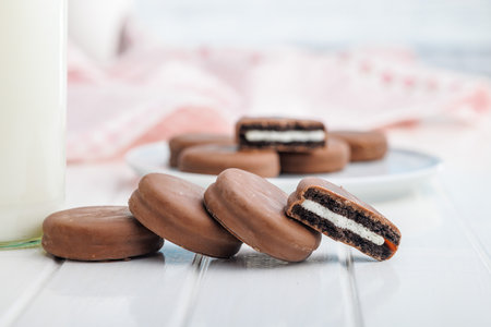 Chocolate Covered Cookies and Glass of Milk on a white table.の写真素材
