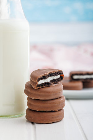 Chocolate Covered Cookies and Glass of Milk on a white table.の写真素材