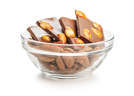 Broken chocolate bar with almonds in bowl isolated on a white background.の写真素材