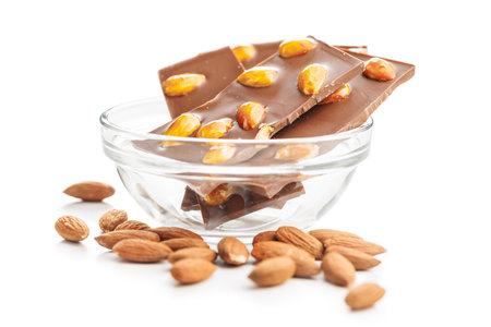 Broken chocolate bar with almonds in bowl isolated on a white background.の写真素材