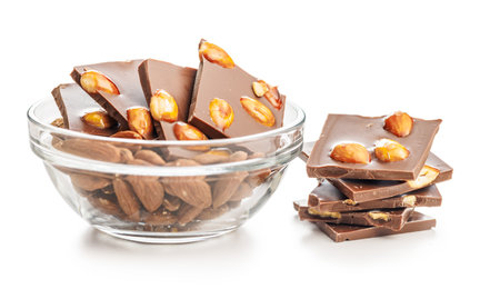Broken chocolate bar with almonds in bowl isolated on a white background.の写真素材