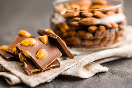 Broken chocolate bar with almonds on a kitchen table.の写真素材