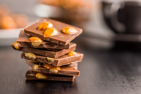 Broken chocolate bar with almonds on a black table.