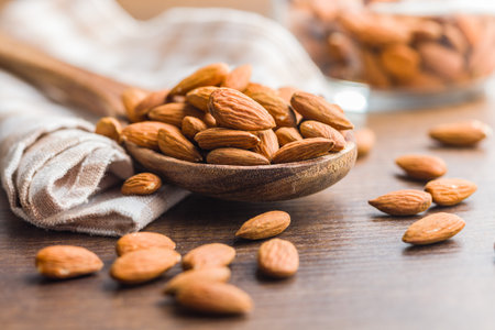 Peeled almond nuts in wooden scoop on a wooden table.の写真素材