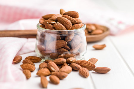Peeled almond nuts in a jar on a white table.の写真素材