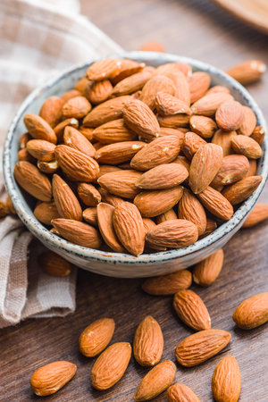 Peeled almond nuts in a bowl on a wooden table.の写真素材