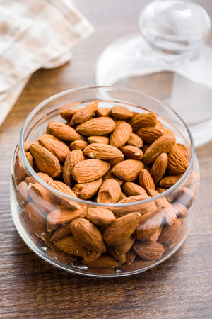 Peeled almond nuts in jar on a wooden table.の写真素材