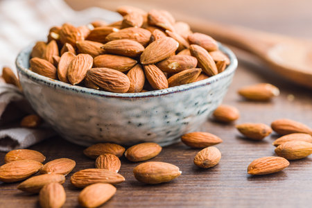 Peeled almond nuts in a bowl on a wooden table.の写真素材