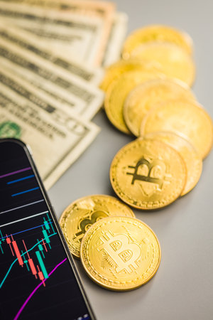 Bitcoin gold coin and american dollars. Cryptocurrency and business chart in a cellphone.の写真素材