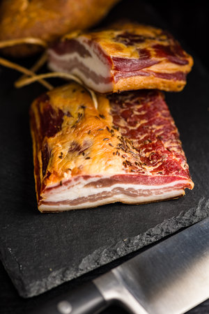 Closeup of Sliced Smoked Bacon on a Black Slate Cutting Boardの写真素材