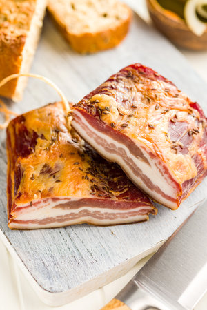 Closeup of Sliced Smoked Bacon on a white Cutting Boardの写真素材