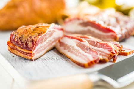 Closeup of Sliced Smoked Bacon on a white Cutting Boardの写真素材