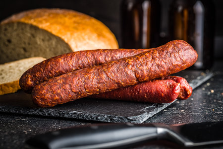 Smoked salami sausages on a cutting board on a black table.の写真素材