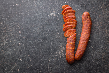 Sliced smoked salami sausage on black table. Top view.の写真素材
