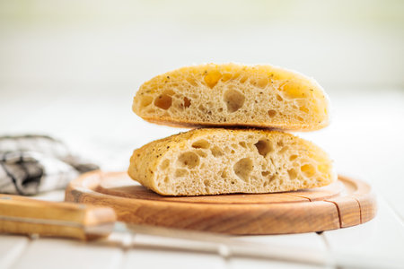 Italian ciabatta bread on a cutting board on a white table.の写真素材