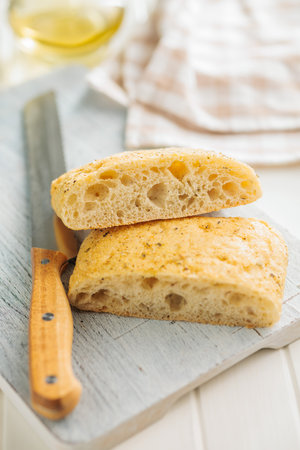 Italian ciabatta bread on a cutting board on a white table.の写真素材