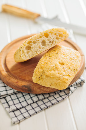 Italian ciabatta bread on a cutting board on a white table.の写真素材