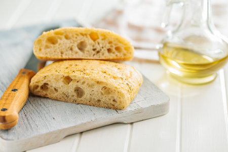 Italian ciabatta bread on a cutting board on a white table.の写真素材