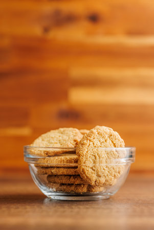 Tasty oatmeal cookies in a bowl on a wooden table.