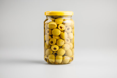 Pickled green olives in brine in a jar on a gray background.の写真素材