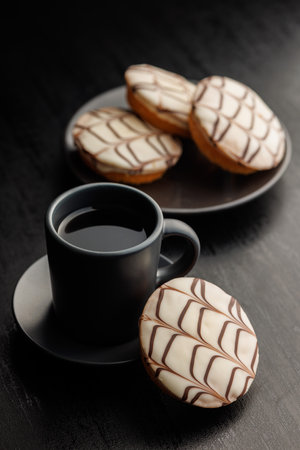 Sweet dessert with sugar coating and coffee mug on a black table.の写真素材