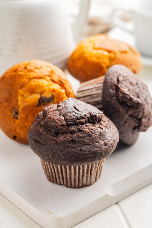 Sweet muffin cakes on a cutting board on a white table.の写真素材