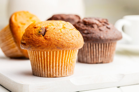 Sweet muffin cakes on a cutting board on a white table.の写真素材