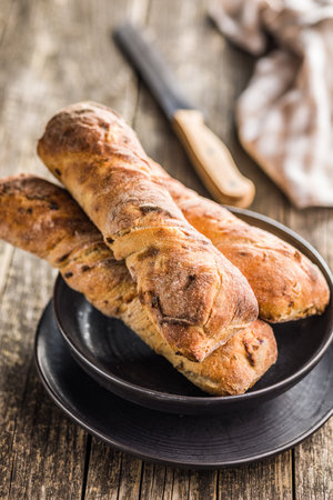 Crusty rustic baguette on a plate on a wooden table.の写真素材