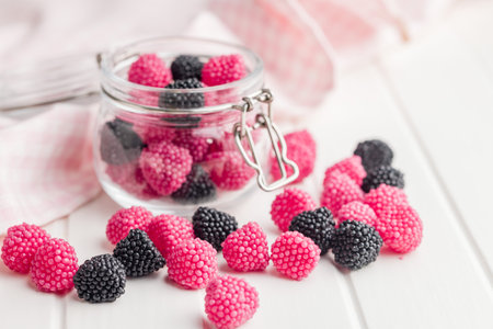 Sweet jelly candies in a jar on a white table.の写真素材