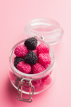 Sweet jelly candies in a jar on a pink background.の写真素材