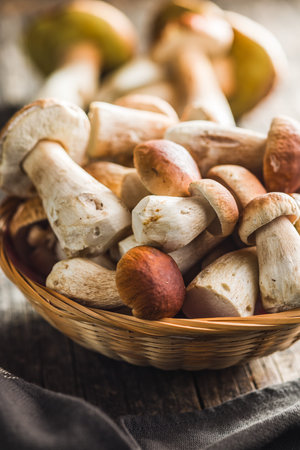 Fresh boletus mushrooms in basket on a wooden table.の写真素材