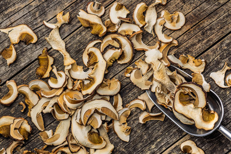 Dried porcini mushrooms. Sliced boletus in a scoop on a wooden table. Top view.の写真素材