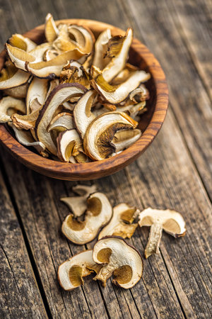 Dried porcini mushrooms. Sliced boletus in a bowl on a wooden table.の写真素材