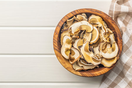 Dried porcini mushrooms. Sliced boletus in a bowl on a white table. Top view.の写真素材