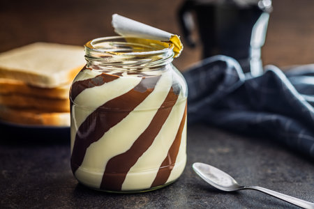 Chocolate cream spread in a jar on a black table.の写真素材