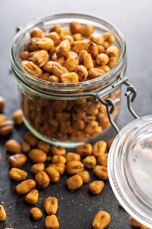 Roasted salted corn snack in jar on a black table.の写真素材