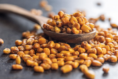 Roasted salted corn snack on a spoon on a black table.の写真素材