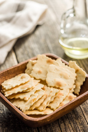 A crispy salted crackers in a bowl on a wooden table.の写真素材