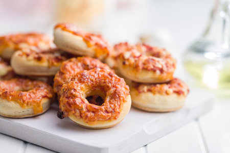 Mini pizza bagels on a cutting board on a white table.の写真素材