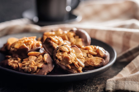Photography of chocolate Florentine cookies with almonds and chocolate on plate on a black table.の写真素材