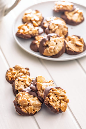 Photography of chocolate Florentine cookies with almonds and chocolate on a white table.の写真素材
